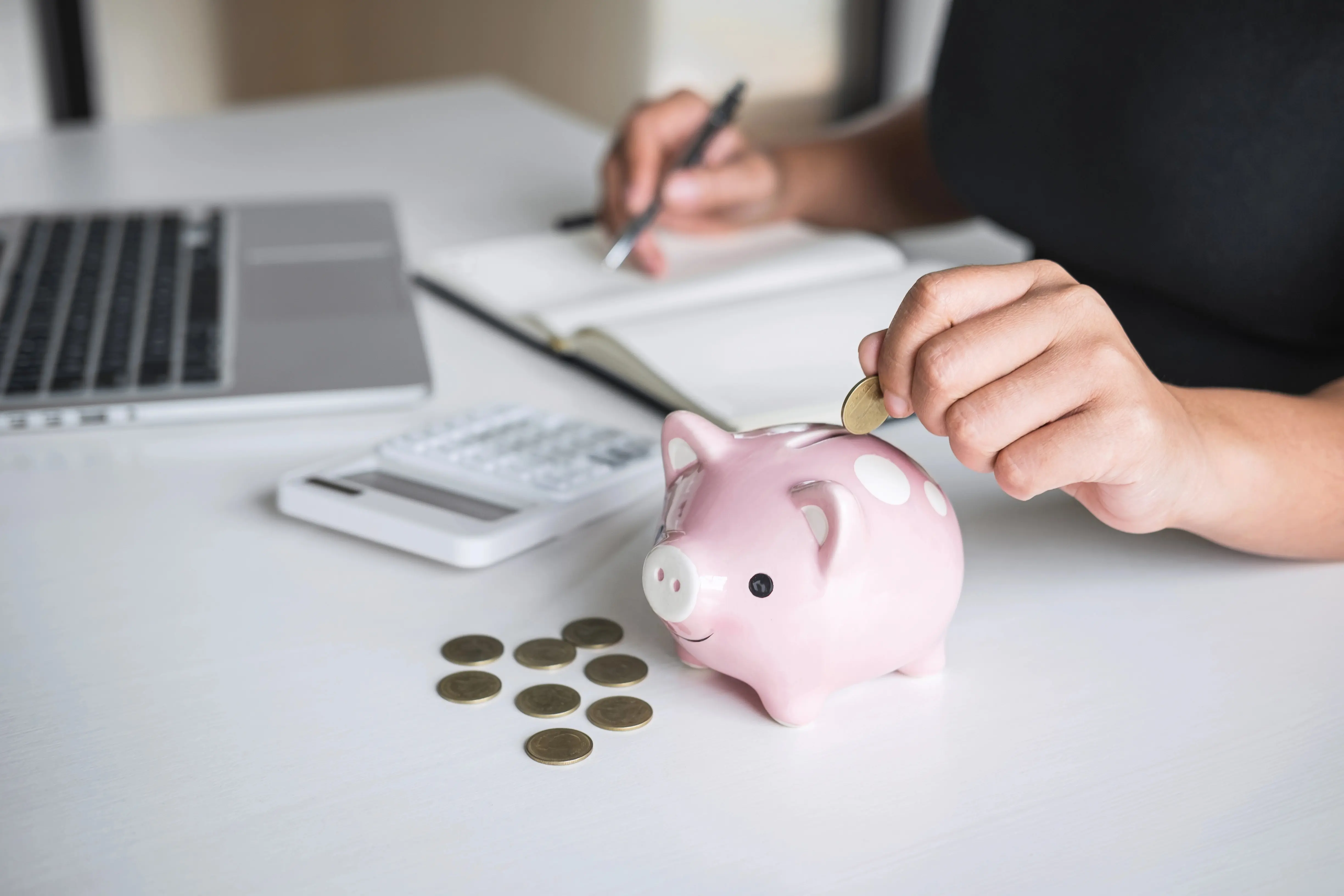 Woman counting money on table with piggy bank