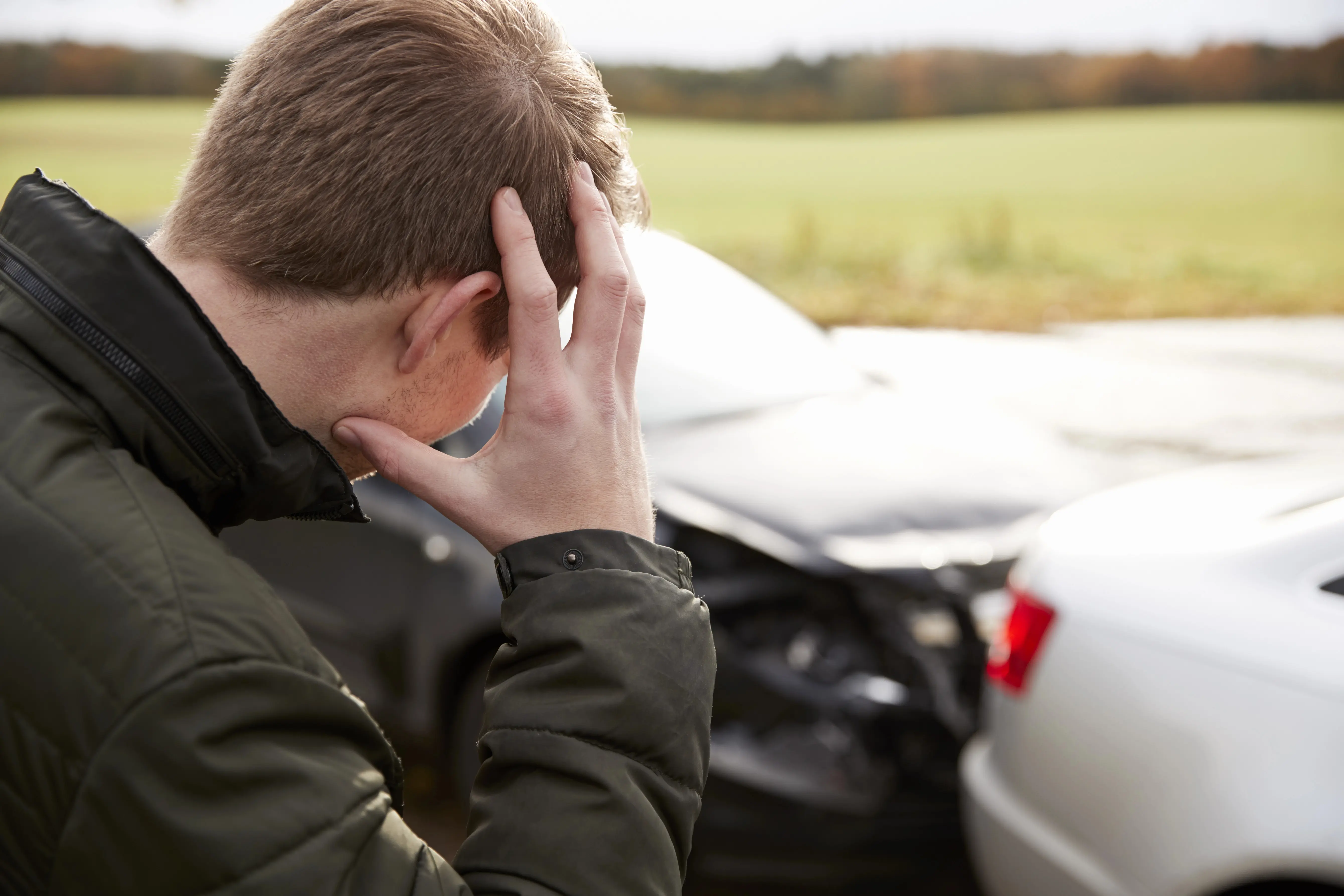 Frustrated man standing in front of damaged car
