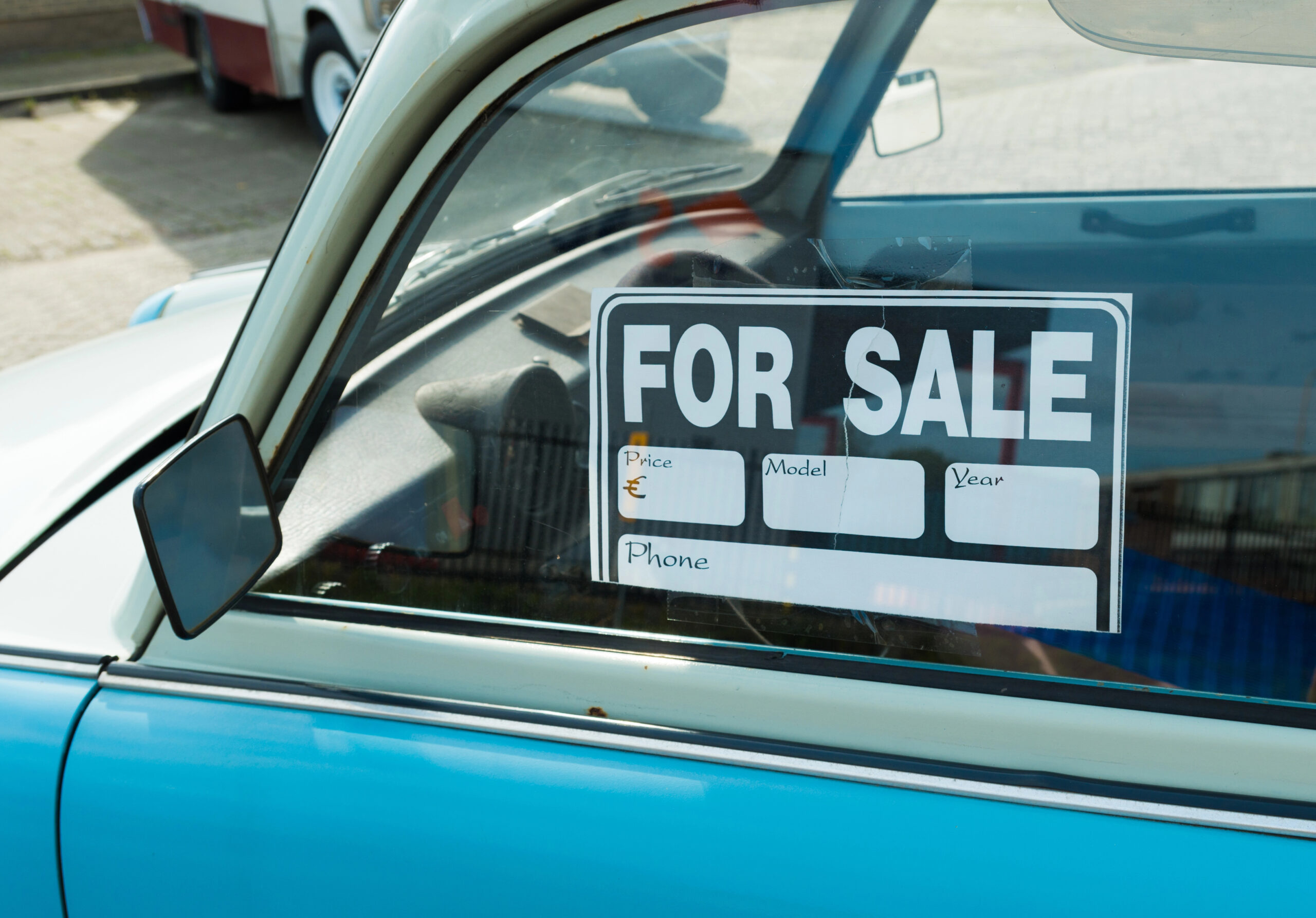 Blue car with for sale sign in the driver side window
