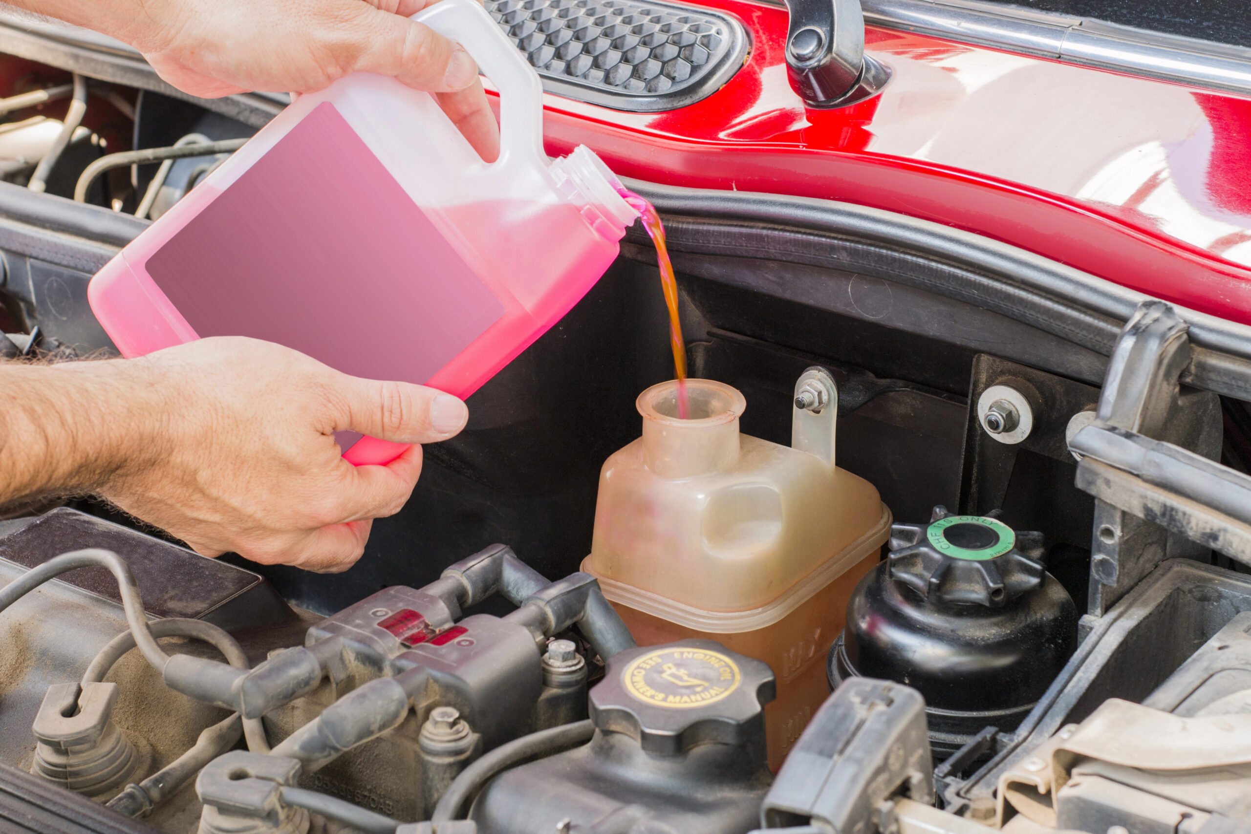 Someone pouring coolant into vehicle