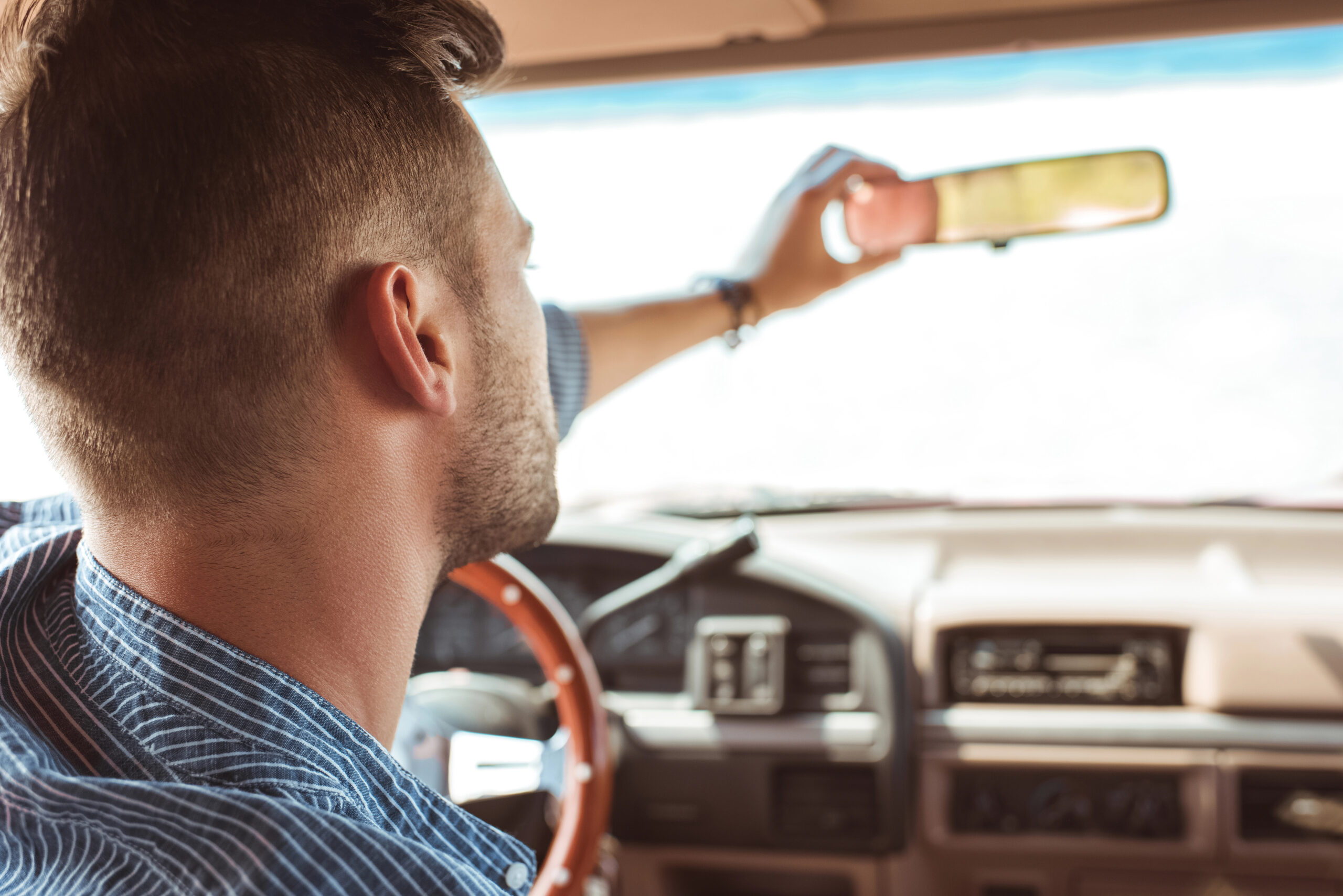 Rearview shot of man adjusting rearview mirror