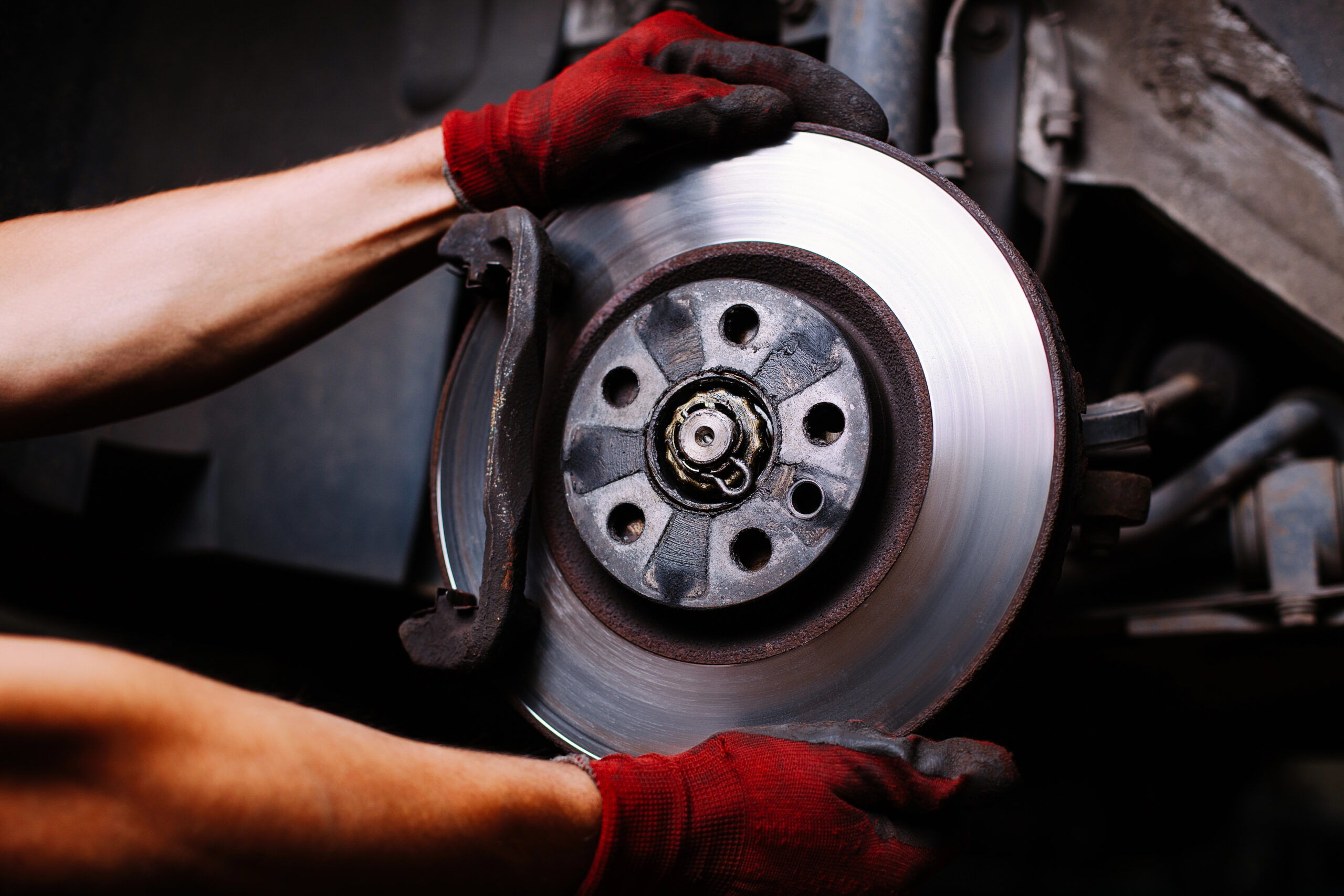 Mechanic touching car brakes with red gloves on.