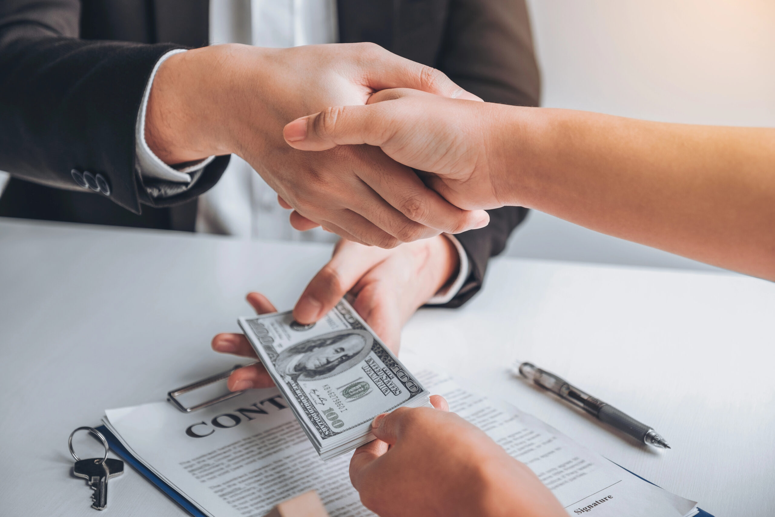 Two hands shaking in agreement over a contract
