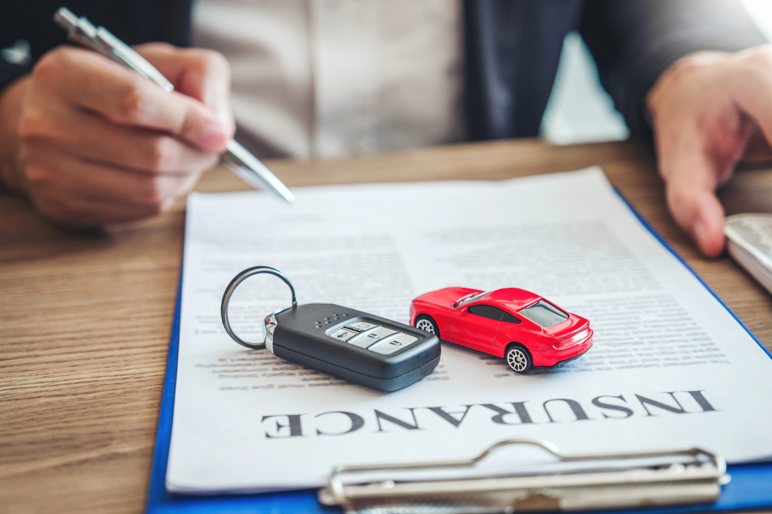 Toy car sitting on a clipboard with car key fob