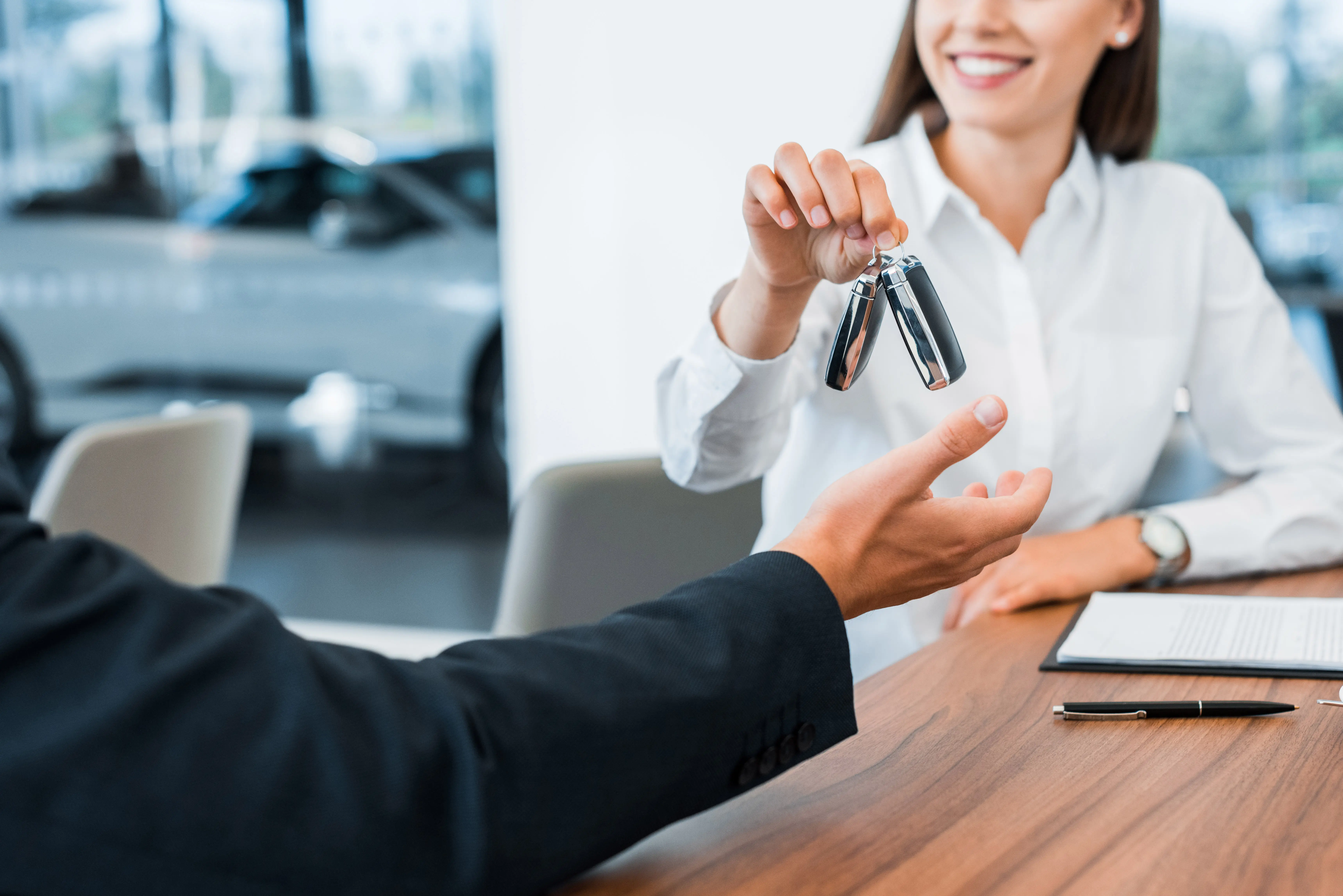 Woman giving new car keys to man