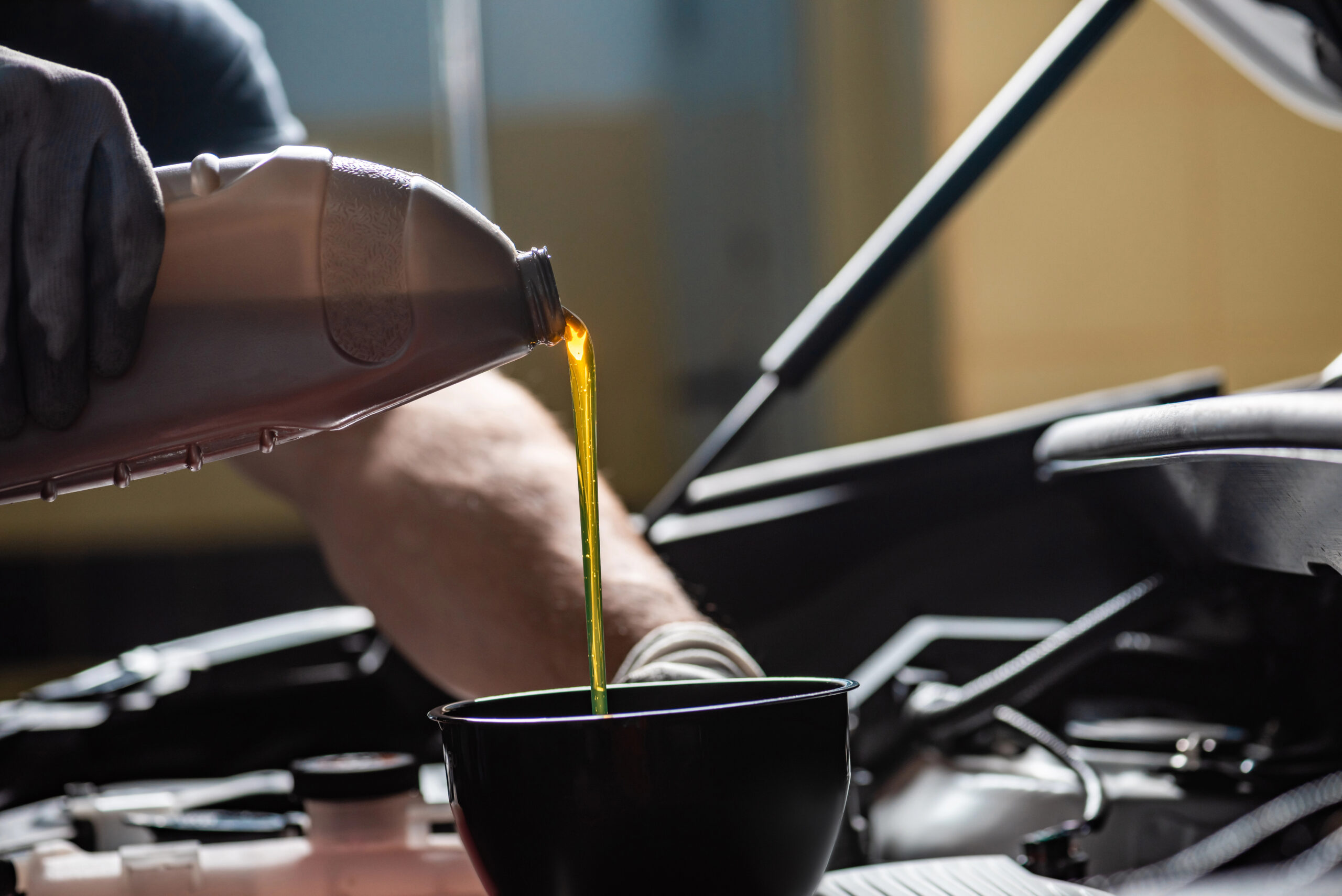 Mechanic pouring engine oil into engine.