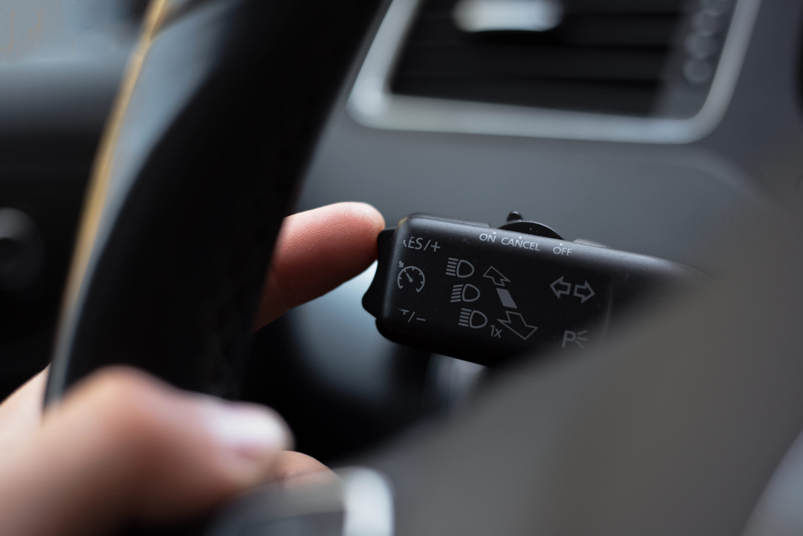 Close up of hand pushing down cruise control button