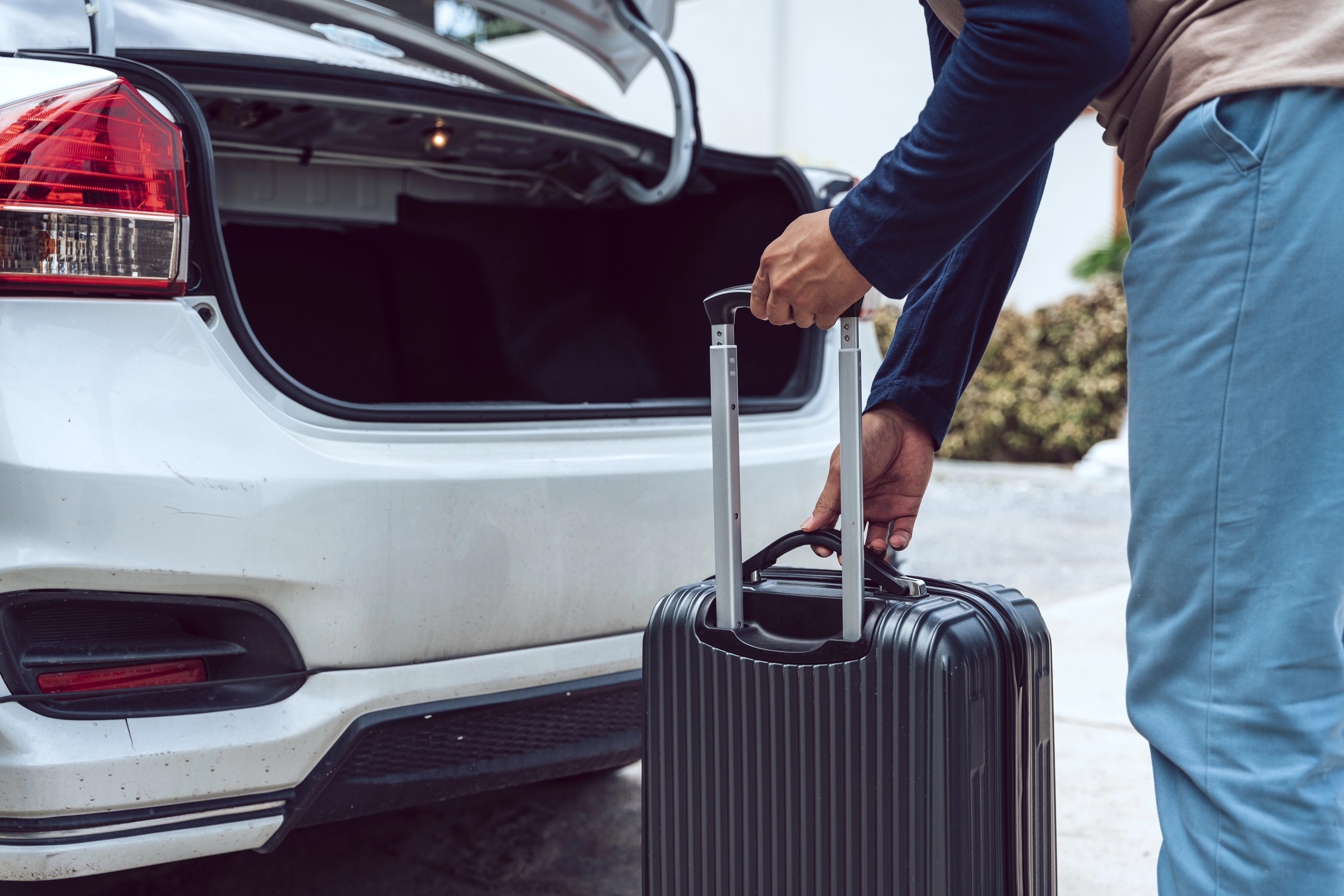 Person loading luggage into trunk of car.