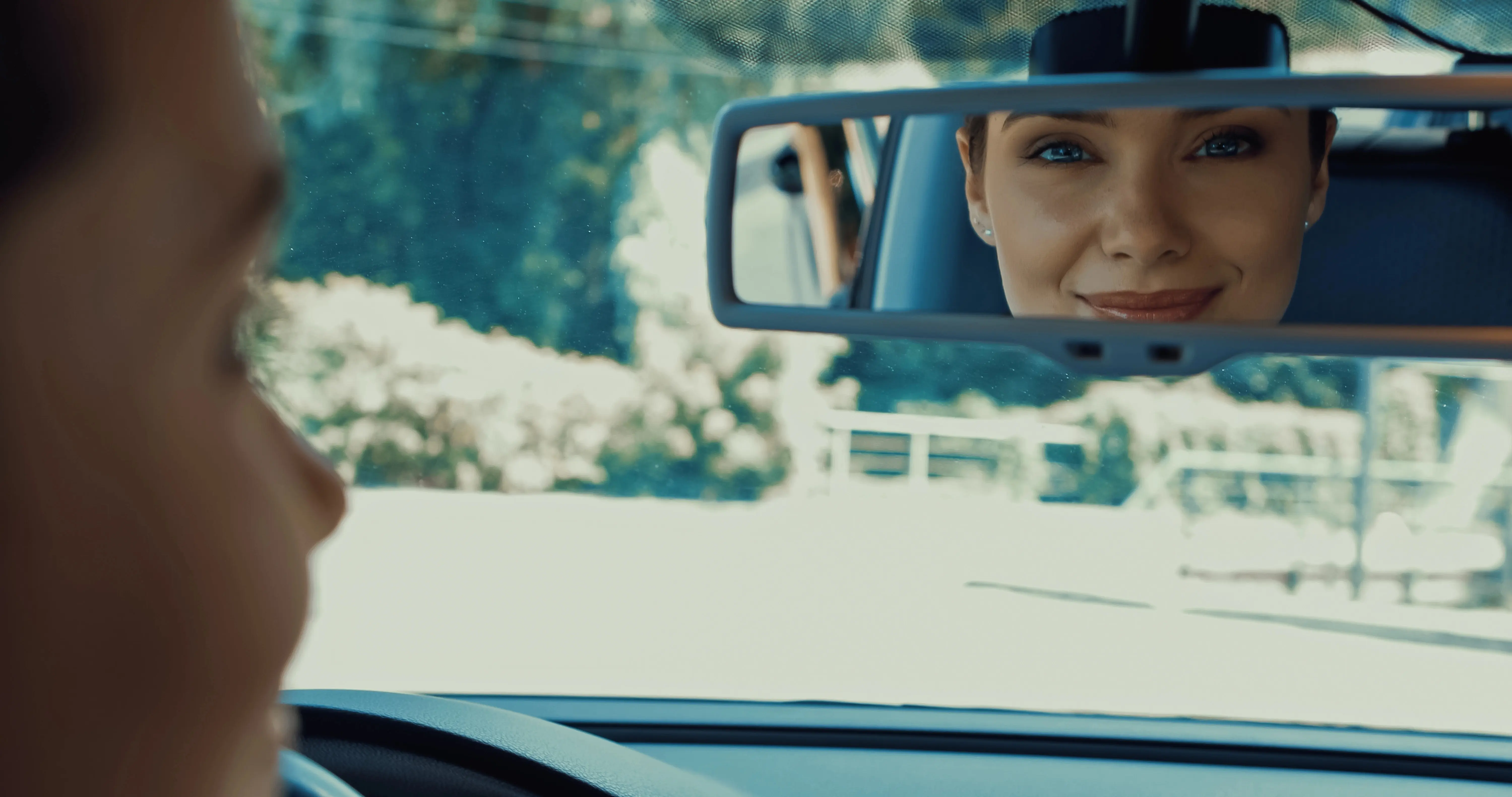 Women looking in rearview mirror.