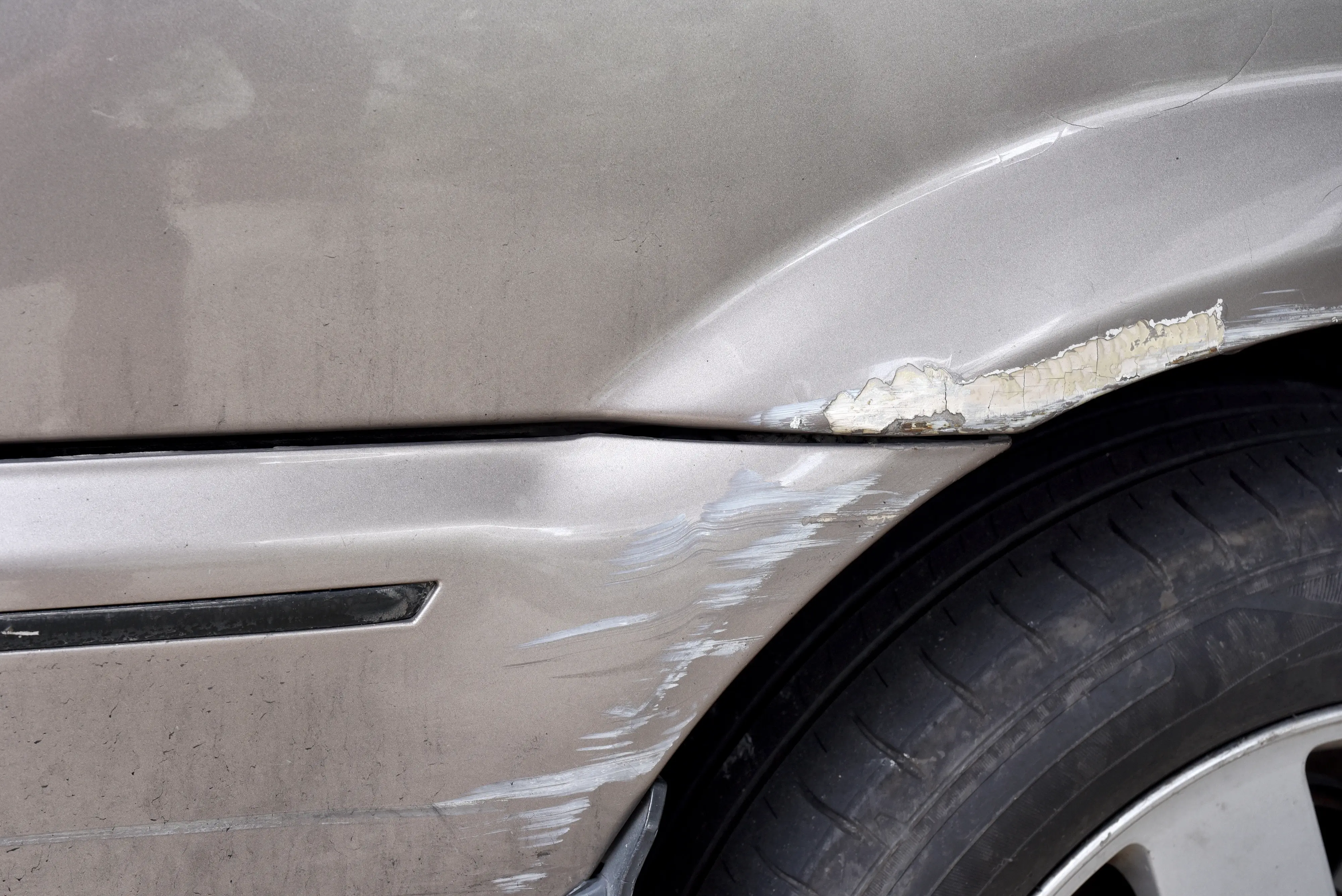 Car with paint scuffs and scratches above rear wheel.