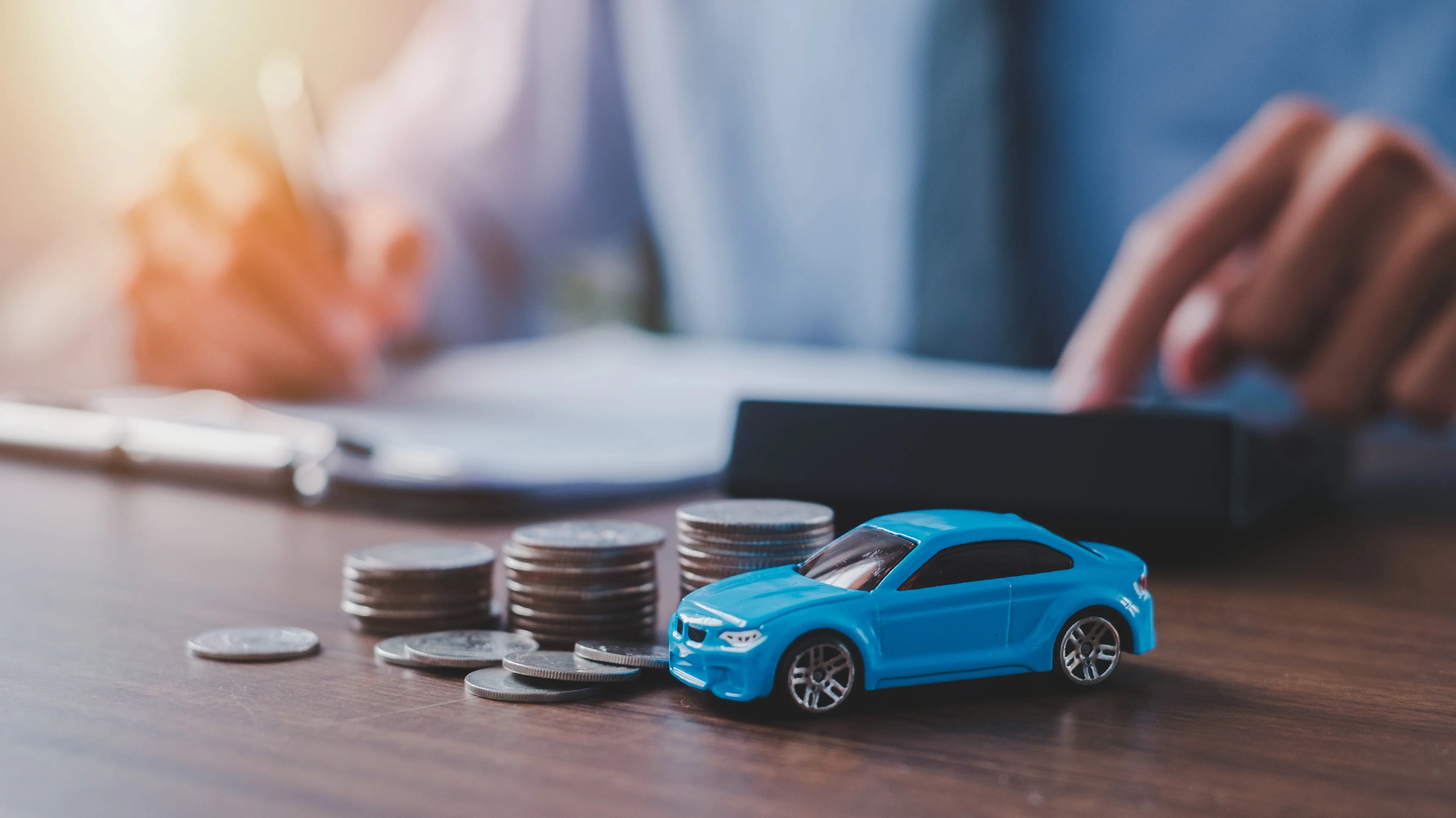 Man using calculator with toy car and cash on table
