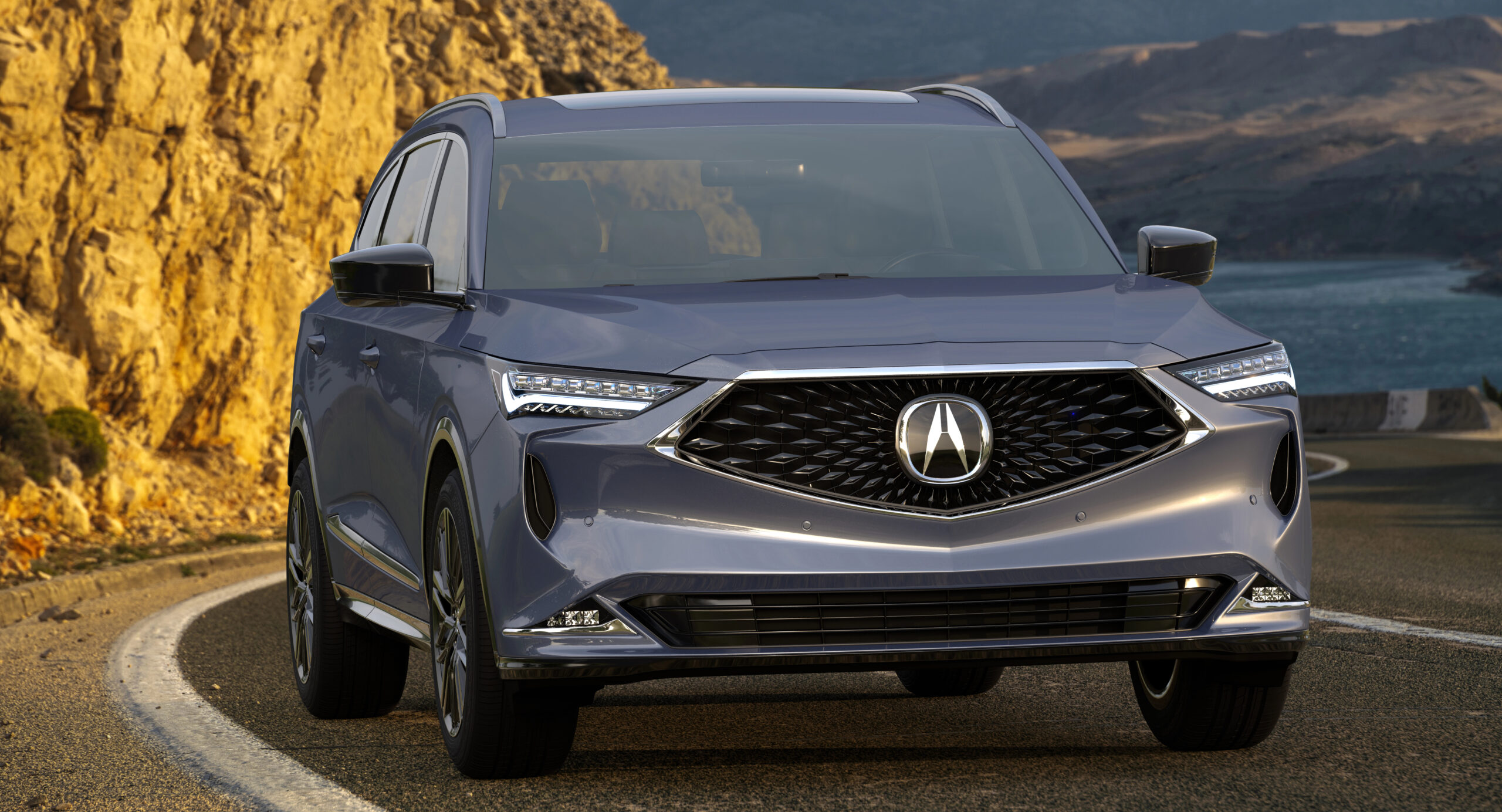 Acura MDX driving in mountain with lake in the background