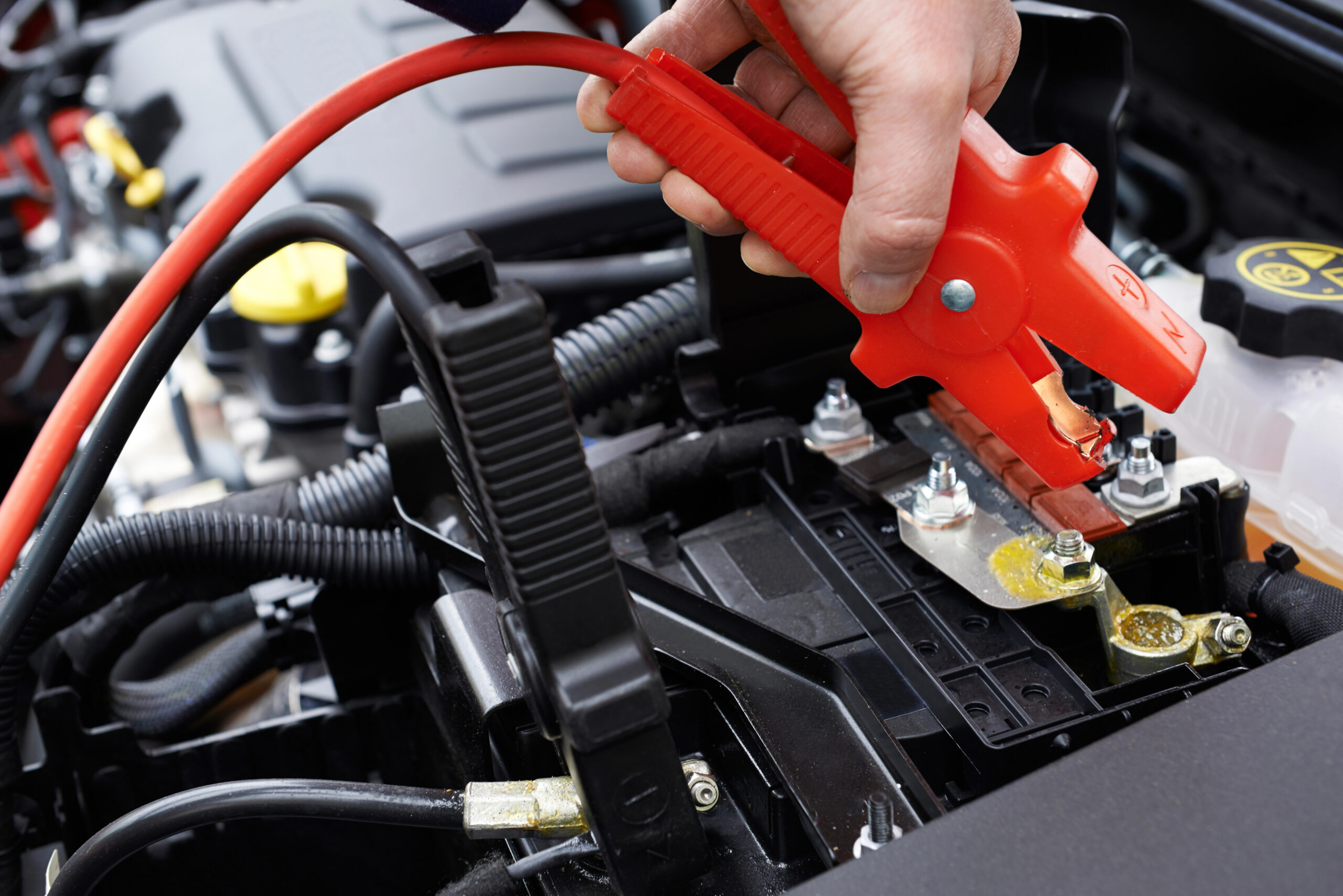 Close-up of someone attaching jumper cables to car.
