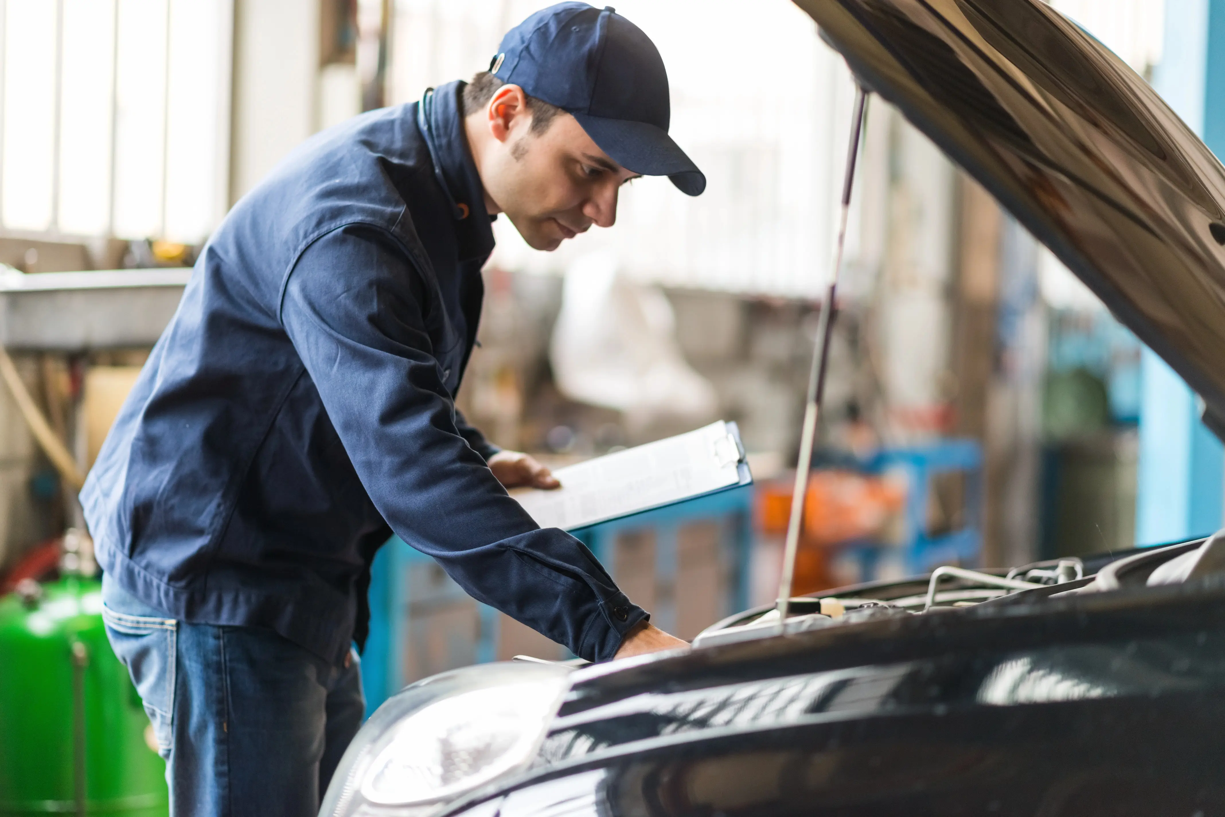 Mechanic inspecting car with a clipboard in hand.