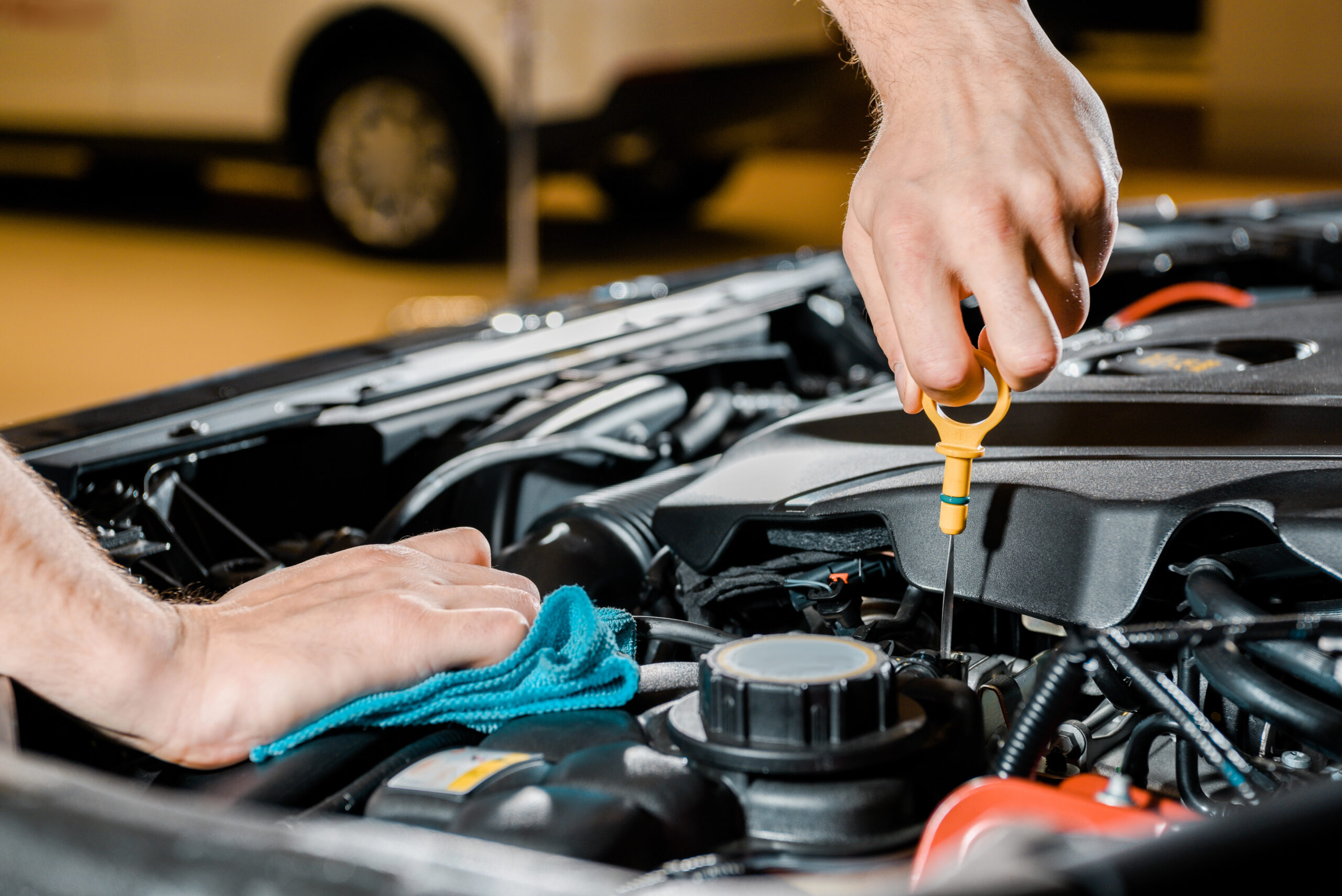 Auto mechanic checking car with rag in hand.